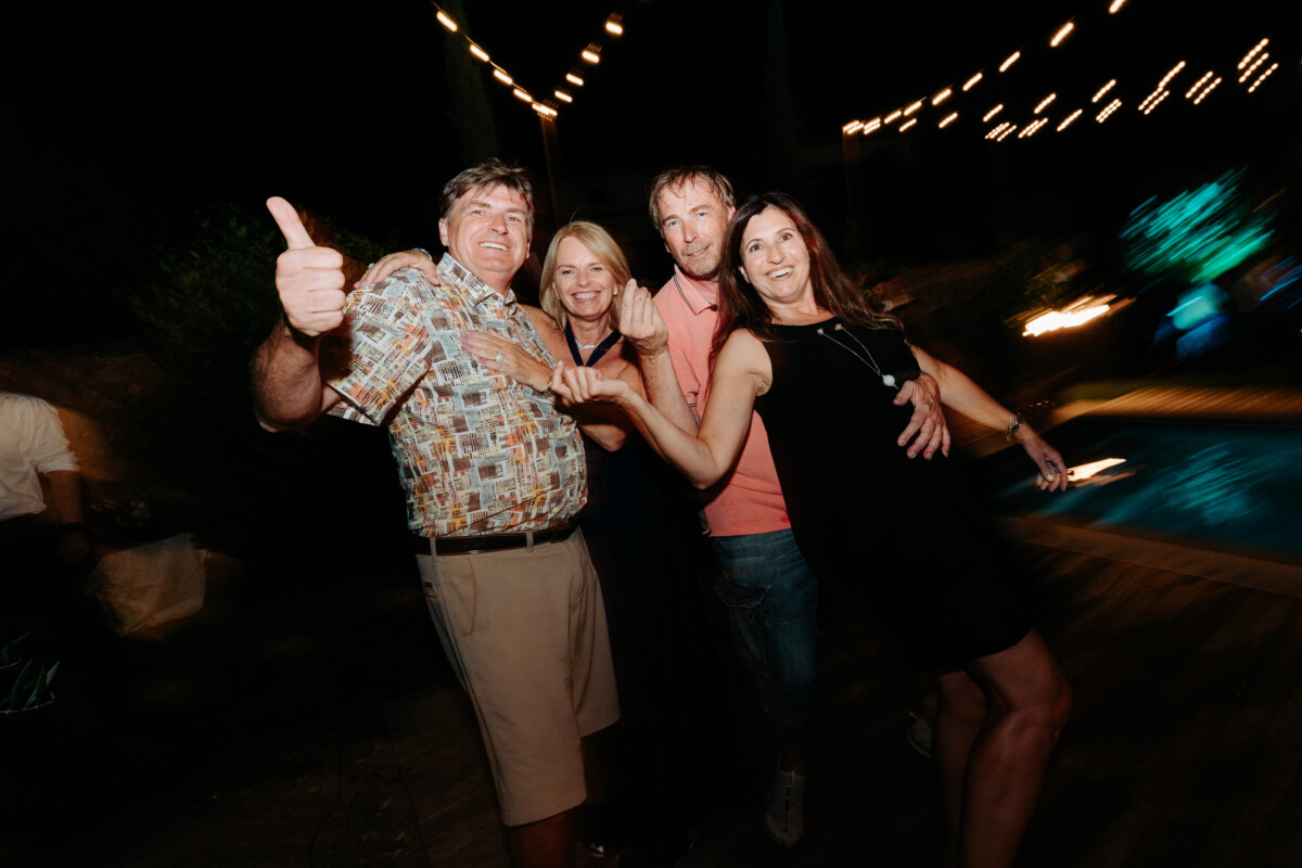 Four individuals posing together with smiles at a social gathering in the evening.